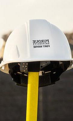 Construction helmet on a shovel with a backhoe in the background